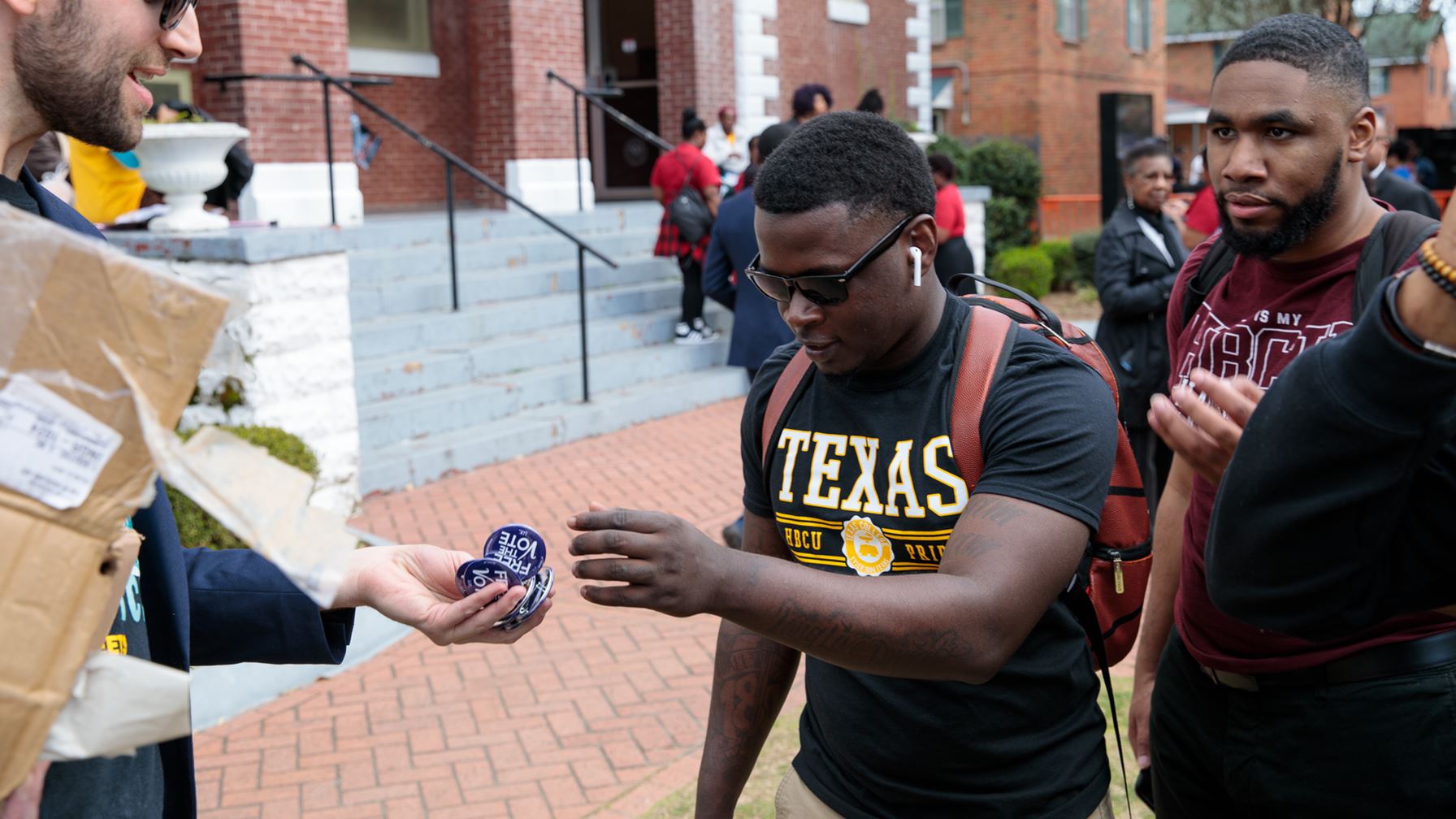 University students on a campus exchanging buttons that read "Free the Vote"
