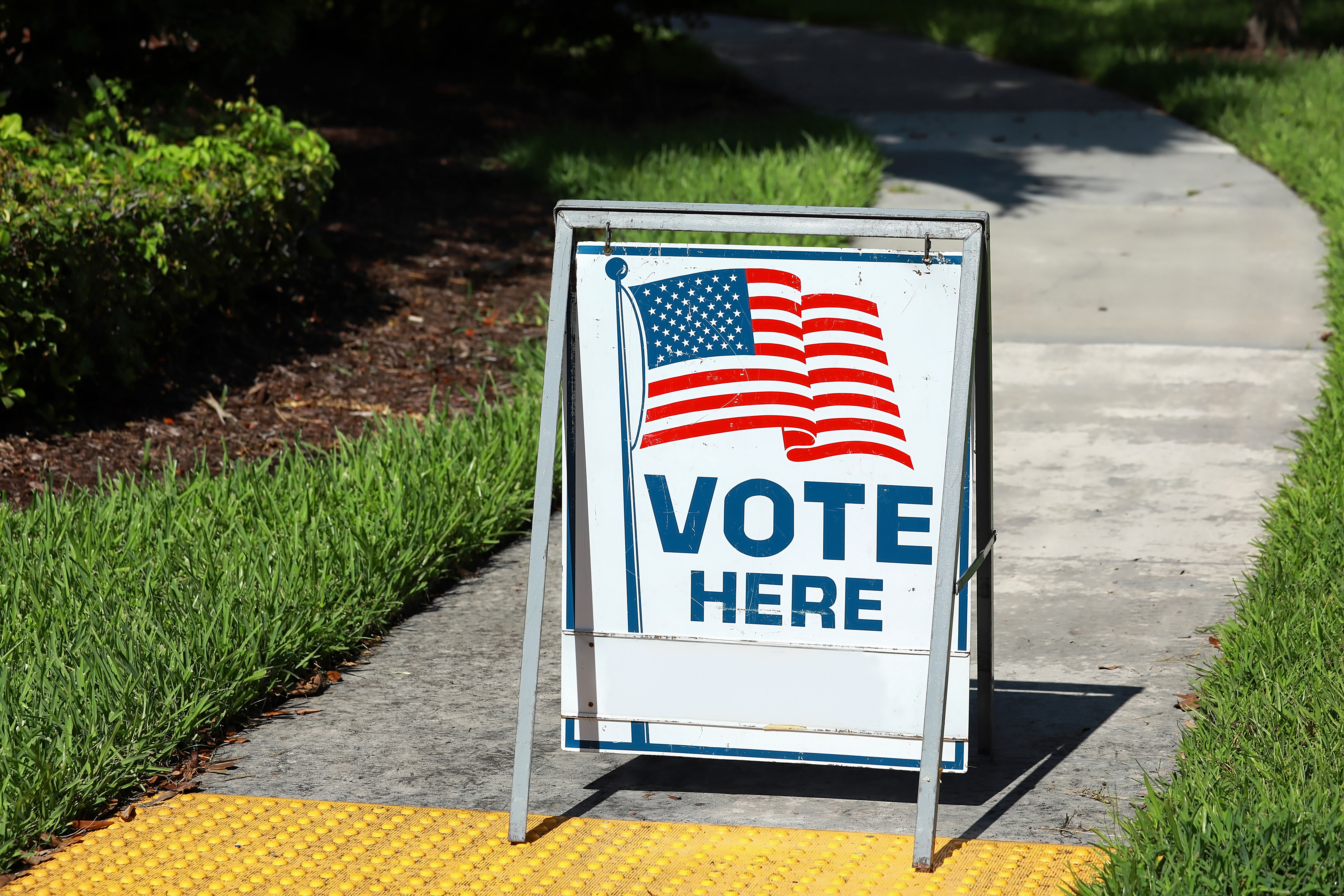 "Vote here" sign on sidewalk