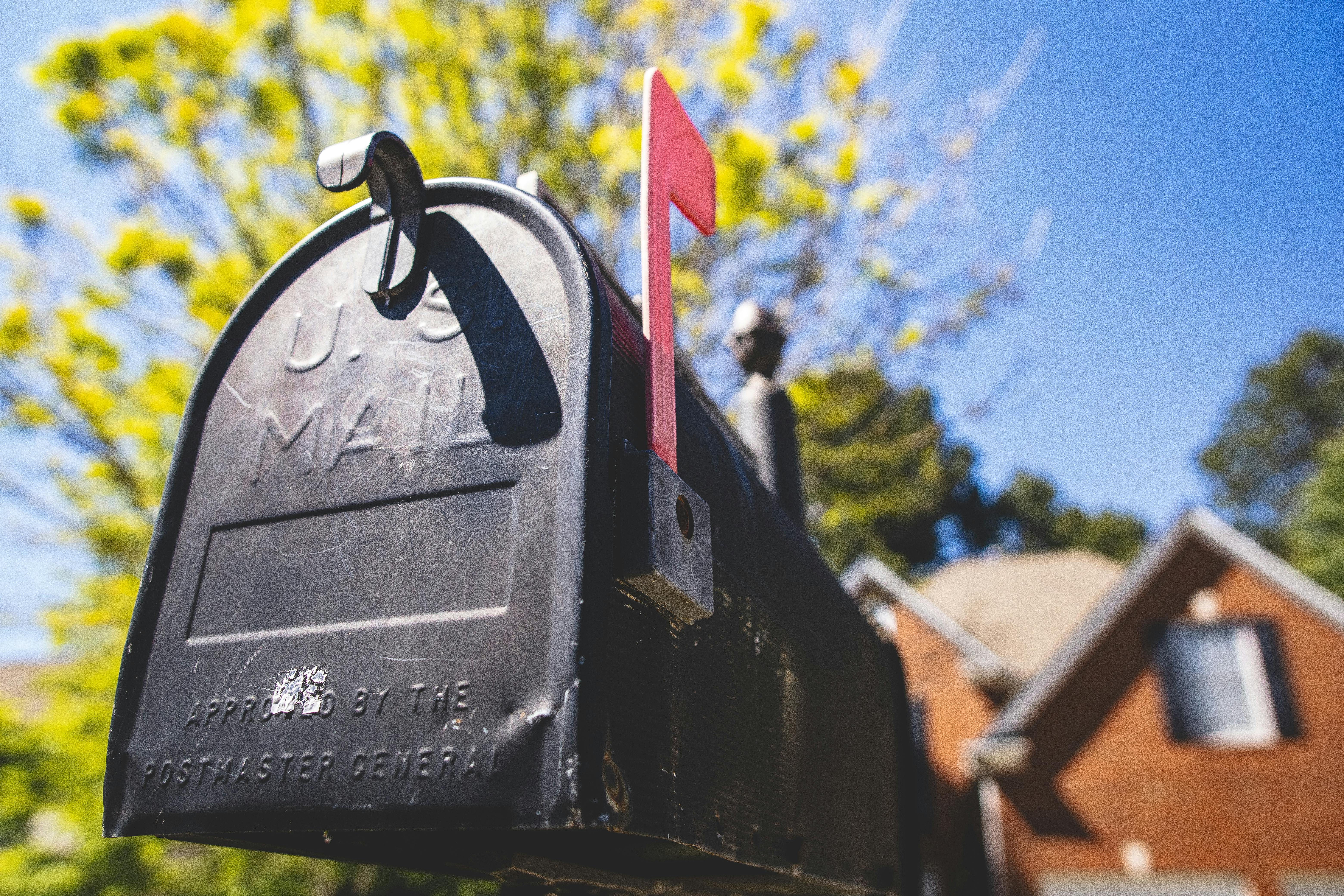 Mailbox with its flag up in front of a defocused brick house