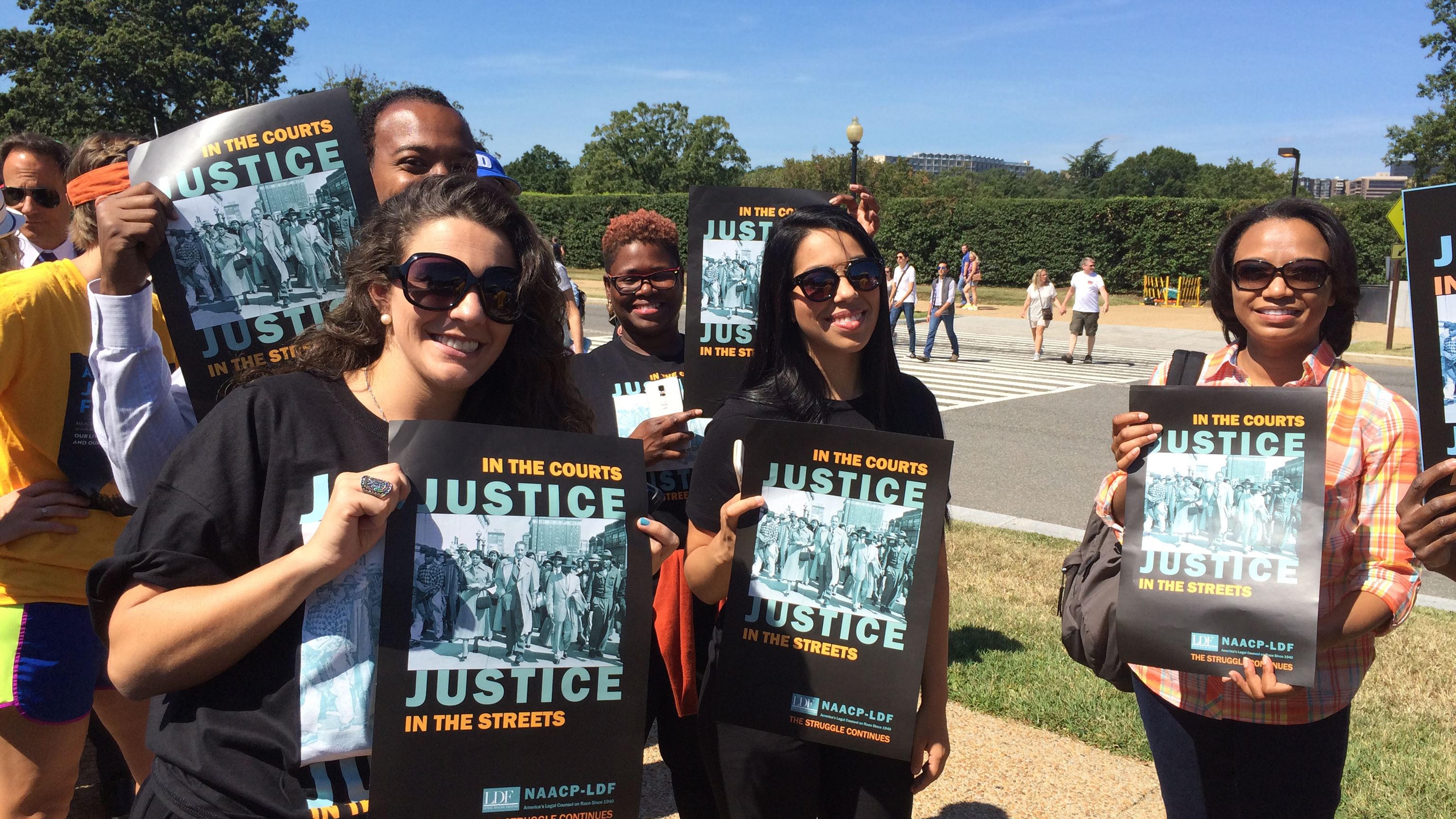 Group of people holding posters with the text Justice. 