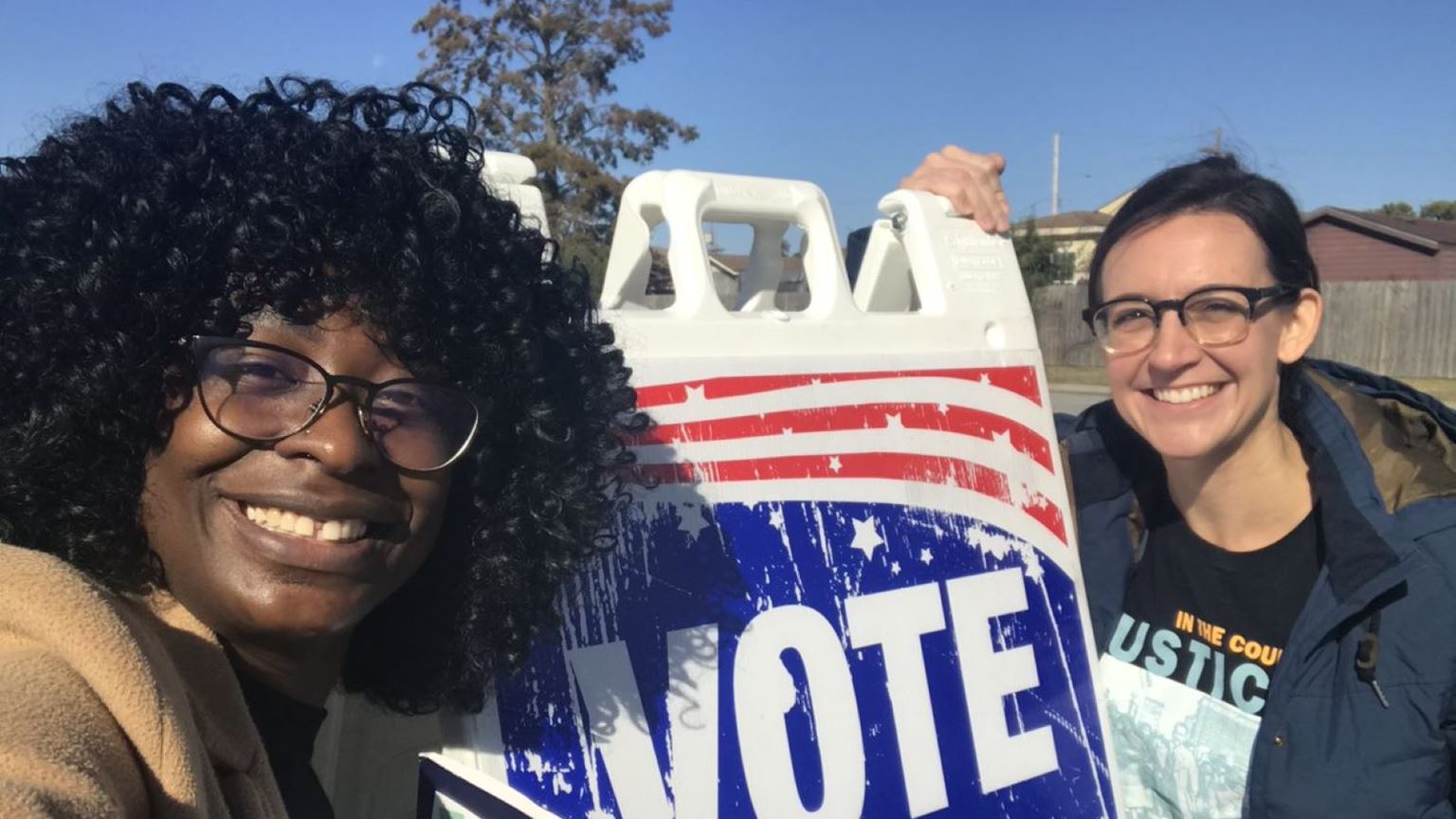 Two women near a sign that says ‘Vote here’.